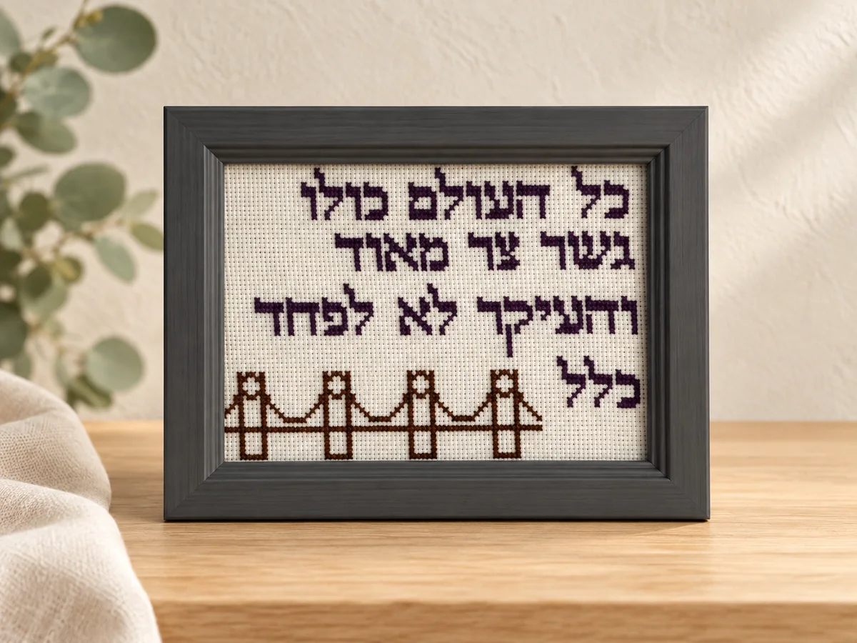 רקמה ממוסגרת עם ציור גשר וכיתוב בעברית